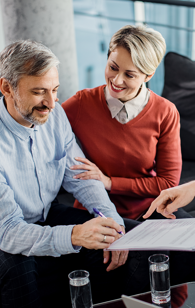 happy mid adult couple signing contract with their agent office