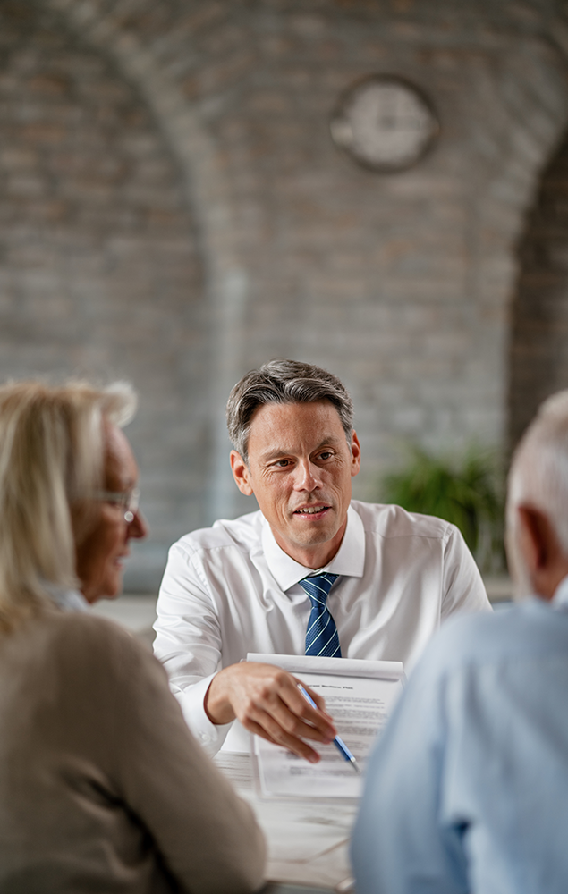 smiling bank manager showing his senior customers where sign contract during meeting office